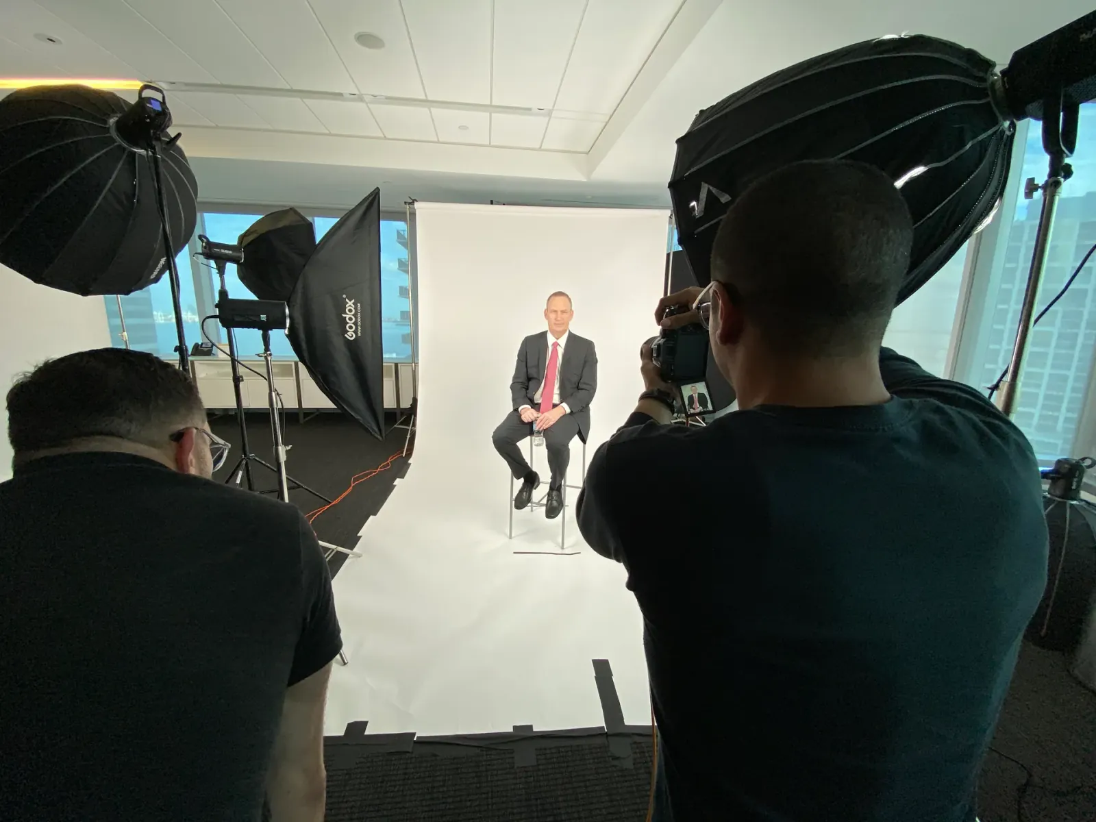 Corporate video production crew filming an executive with professional studio lighting